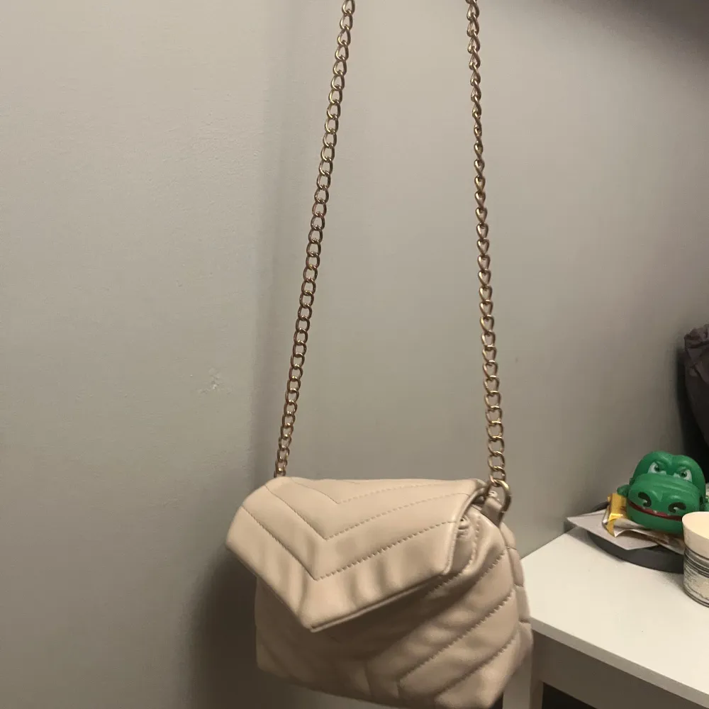 Den är använd för länge sen men inte sliten. En beige väska med guld kedja. Säljs då den inte används! . Laukut & Käsilaukut.