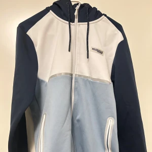 Blå och vit huvtröja från McKenzie - Säljer en snygg huvtröja från McKenzie i blått och vitt. Den har en dragkedja framtill och praktiska fickor. Pris går att diskutera och den är ganska ny och används bara 2 gånger. Nypriss 600kr mitt pris 229. Vid frågor, skriv. 