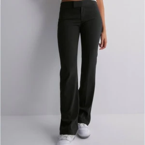Svarta bootcut byxor - Säljer ett par snygga svarta bootcut byxor. De är lågmidjade och har en tight passform upptill som övergår i en utsvängd stil vid benen. Perfekta för både vardag och fest!