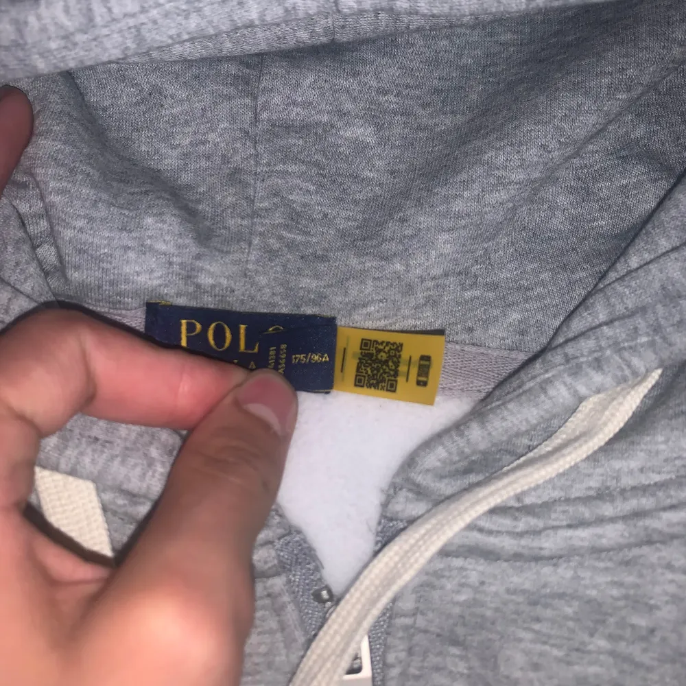 Mycket fin grå polo zip upp hoddie med mörkblå logo som är märklig och väldigt unik, materialet är jättte skönt och värdigt för det kalla vädret. Hoodies.