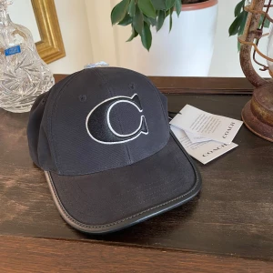 COACH keps med läderdetaljer - Svart COACH keps köpt i USA med äkta läder detaljer. Mycket bra kvalitet. Storlek M/L. Kostade 95$ (≈985kr). Kontakta mig vid alla frågor och funderingar. 