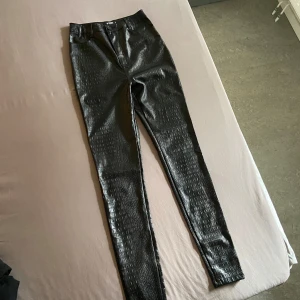 Svarta byxor med krokodilstruktur från Missguided - Säljer ett par svarta byxor från Missguided TALL i storlek 36. De har en cool krokodilstruktur. Byxorna är högmidjade och har en slim passform. Otroligt snygga på! 