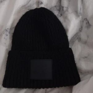 Svart stickad mössa från Kappahl - Säljer en svart stickad mössa från Kappahl. Har en design med en diskret logga framtill. Mössan är i one size och passar de flesta. Nypris 99kr. Går att skriva till mig ifall du vill ha den lite billigare!💕