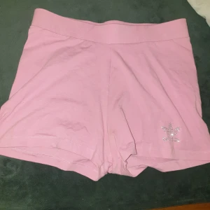 Rosa shorts från Adidas - Säljer ett par nya superbekväma rosa shorts från Adidas. De är gjorda i mjukt bomullsmaterial och har en snygg glittrig Adidas-logga på ena benet. Perfekta för en avslappnad dag eller träning. De har en normal passform och är midwaist. Passar S o M.