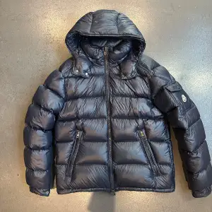 Fet mörkblå moncler jacka i modellen maya! Jackan är knappast använd och är i ny skick, alltså inga defekter. Taggen ingår också! Jackan är i storlek 2 vilket motsvarar ungefär storlek M.  Skriv i pm vid frågor eller om ni vill ha fler bilder!