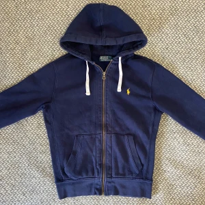 Ralph lauren hoodie - Mörkblå ziphoodie från polo ralph lauren. Storlek M, sitter som en S/M. I mycket fint skick, en liten fläck på baksidan av ärmen men annars inga skador eller liknande. Hör gärna av dig vid frågor😉👊🏽
