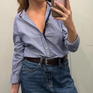 Blå och vit randig skjorta från Zara - Säljer en snygg blå och vit randig skjorta från Zara i storlek M. Skjortan har en relaxed fit och är perfekt för både vardag och fest. Den har långa ärmar och knappar hela vägen ner. Superbekväm och stilren!