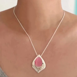 Halsband  - Snyggt halsband med en stor rosa sten i mitten. Hänget har en unik form som liknar ett blad eller en droppe, vilket ger det en modern och stilren look. Perfekt för att piffa upp vilken outfit som helst! Aldrig använt! 