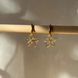 Guldörhängen med blomdesign - Säljer ett par superfina guldörhängen med en söt blomdesign. De är perfekta för att ge en elegant touch till vilken outfit som helst. Örhängena har en enkel och stilren look som passar både till vardags och fest. 🌼✨ helt nya handgjorda 