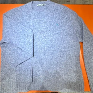 Grå ulltröja från Acne Studios - Säljer en snygg och stilren grå ulltröja från Acne Studios. Tröjan har en liten broderad logga på bröstet i blått och grönt. Perfekt för kyliga dagar och passar både till vardags och lite finare tillfällen. Supermjuk och bekväm att ha på sig! Storleksmässigt känns den mindre än L men acne är ju lite udda.