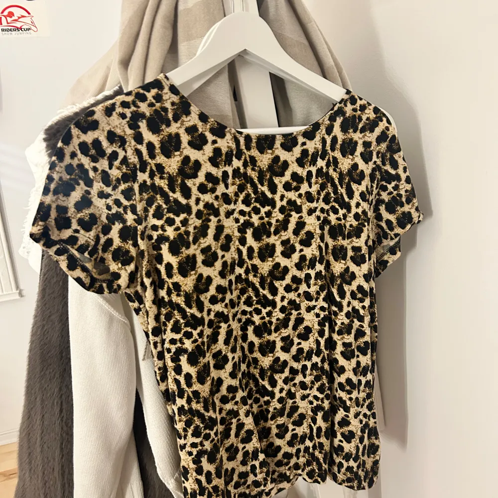 Snygg leopardmönstrad topp i beige och svart. Perfekt för en utekväll eller fest! Den har korta ärmar och en bekväm passform. Ett måste för garderoben om du gillar djurmönster!. Toppar.