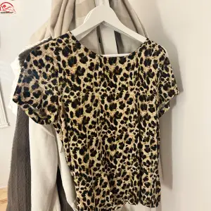 Snygg leopardmönstrad topp i beige och svart. Perfekt för en utekväll eller fest! Den har korta ärmar och en bekväm passform. Ett måste för garderoben om du gillar djurmönster!