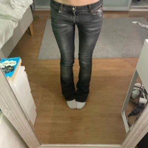 Grå jeans med bootcut - Säljer ett par grå jeans i bootcut-stil. De är lågmidjade och har en snygg tvätt som ger en cool look. De är i bra skick men har lite slitage vid fållen. Passar perfekt till sneakers eller boots. I storlek 27