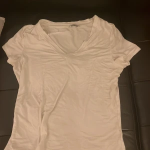 Vit v-ringad t-shirt - Säljer en klassisk vit v-ringad t-shirt i bomull. Perfekt för vardagsbruk eller som basplagg i garderoben. Den har en normal passform och korta ärmar. Enkelt och stilrent val för alla tillfällen. Sitter bra vid brösten. Från Cubus 