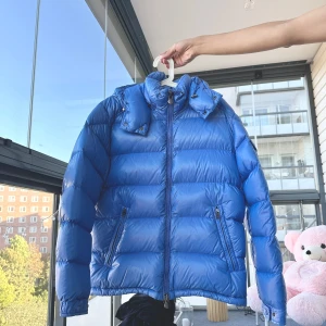 Blå dunjacka från Moncler maya str 3  - Säljer en snygg blå maya dunjacka från Moncler. Moncler maya sky blue eller light blue, storlek 3 som passar M-L. Mycket bra skick. Den är perfekt för vintern med sin varma och puffiga design. Jackan har en dragkedja framtill och en praktisk huva. Den är i mycket bra skick och redo för kalla dagar. Passar perfekt för både vardag och vinteräventyr! Kvitto och en tag  finns 