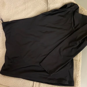 Svart långärmad topp från H&M - Säljer en stilren svart långärmad topp från H&M i storlek M. Perfekt för både vardag och fest. Materialet känns mjukt och bekvämt mot huden. Toppen har en enkel design som gör den lätt att matcha med olika outfits. Passa på att fynda denna mångsidiga topp!