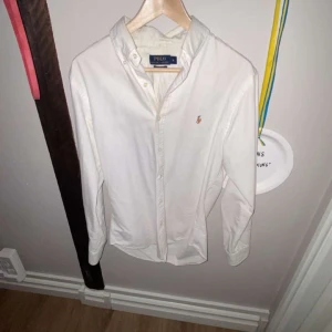 Vit skjorta från Polo Ralph Lauren - Säljer en klassisk vit skjorta från Polo Ralph Lauren i mycket bra skick. Skjortan har långa ärmar och en broderad logga på bröstet. Perfekt för både vardag och fest! 🕺PRISET EJ HUGGET I STEN!!!