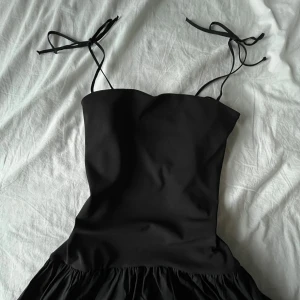 Svart långklänning  - Svart figursydd långklänning med knytbara axelband. Från Zara i Polyester och Elastan, använd en gång.