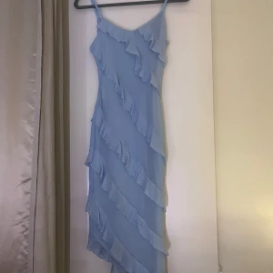 Ljusblå klänning med volanger - Säljer en superfin ljusblå klänning med volanger. Den är axelbandslös och perfekt för sommarens fester. Klänningen har en smickrande passform och är gjord i ett lätt och luftigt material. Perfekt för en dag på stranden eller en kväll ute! 💙