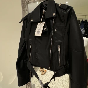 Svart skinnjacka med dragkedjor - Snygg svart skinnjacka från pull&bear i nytt skick. Aldrig använd +frakt