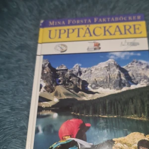 Upptäckare - En bok från serien 'Mina första faktaböcker' med titeln 'Upptäckare'. Omslaget visar en vacker naturbild med berg och en sjö. Boken verkar vara en introduktion till upptäcktsresande och äventyr för yngre läsare.