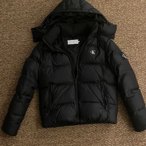 Svart vinterjacka från Calvin Klein Jeans - Hej! Jag säljer nu min Calvin Klein jacka som är perfekt för höst/vinter! Jackan är i mycket bra skick och är i storlek S. Hör av dig vid minsta fundering!😁