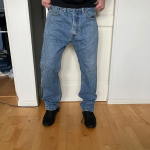 Levi's 505 36-32 - Säljer ett par klassiska Levi's jeans i blå denim. De har en straight passform och är högmidjade, perfekt för en avslappnad stil. Jeansen är i mycket bra skick och har den ikoniska Levi's-lappen på baksidan. Perfekta för både vardag och fest!