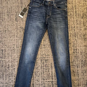 Blå slim jeans från Jack & Jones - Säljer ett par snygga blå slim jeans från Jack & Jones i nytt skick. De har en klassisk femficksdesign och är perfekta för både vardag och fest. Jeansen är tillverkade i ett slitstarkt material och har en bekväm passform. Perfekta för dig som vill ha en stilren look! 💙
