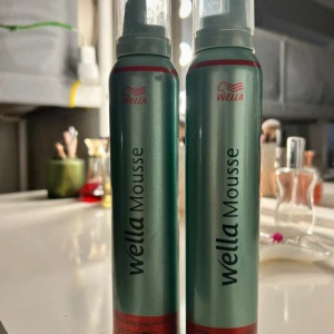 Wella mousse - Två flaskor Wella Mousse för stark stadga. Perfekt för att ge volym och struktur till håret. Flaskan är grön med röd och svart text. Passar alla hårtyper och ger en långvarig effekt.