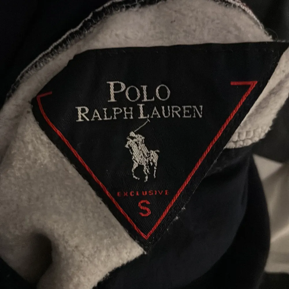 Säljer en snygg och bekväm hoodie från Polo Ralph Lauren i grått och marinblått. Den har en stor logga på framsidan och en praktisk känguruficka. Perfekt för en avslappnad stil eller en kylig dag. Huvan har dragsko för justerbar passform.. Tröjor & Koftor.