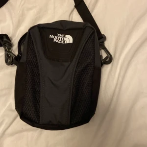 Svart axelväska från The North Face - Northface axelväska för 200kr köpt för 600kr för ca en månad sedan men aldrig använd. Mycket utrymme ungefär lika lång som en sko i storlek 40.