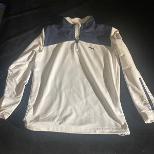 Vit och marinblå tröja från Puma - Säljer en snygg vit och marinblå tröja från Puma i storlek S. Tröjan har en dragkedja vid halsen och långa ärmar med dragkedjor vid ärmsluten. Perfekt för träning eller en avslappnad dag. Den är i mycket bra skick och redo för nya äventyr! 🏃‍♂️