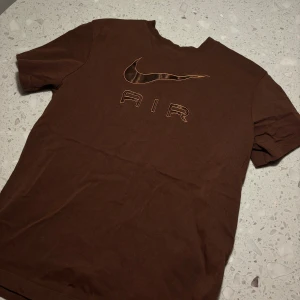 Brun t-shirt från Nike - Säljer en brun t-shirt från Nike i loose fit. Den har en cool Nike Air-logga på framsidan. Perfekt för en avslappnad stil eller träning. Tillverkad i mjukt material för extra komfort.