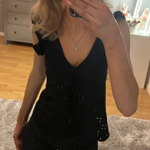 Svart topp med volangärmar från SHEIN - Snygg svart topp från SHEIN med volangärmar och v-ringning. Toppen har en söt knytning framtill och är perfekt för både vardag och fest. Den är i ett lätt och luftigt material, vilket gör den idealisk för sommardagar. Aldrig använd med lappen kvar💕