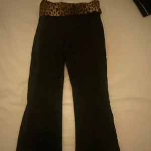 Svarta byxor med leopardmönstrad midja - Säljer ett par svarta yoga pants med en cool leopardmönstrad midja. Byxorna har en bootcut-stil som ger en snygg siluett. Köpt på nån butik i Spanien så vet inte var de är köpta. Säljer för att de aldrig kommer till användning. Jag är 1,65 och de passar perfekt. 