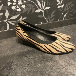 Zebramönstrade skor - Säljer zebramönstrade i beige och svarta skor med liiten klack (se bild 2) från novita i storlek 40. Har fått dom så vet inte hur mycket dom är använda men bara små små tecken på användning på undersulan men syns knappt, annars inga defekter. Köparen betalar frakten!