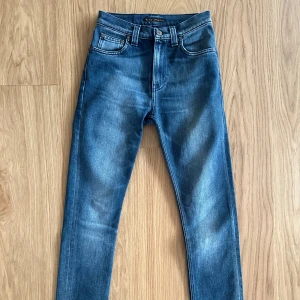 Blå jeans från Nudie Jeans - Snygga jeans med hög midja från Nudie jeans co. Knappt använda, mkt bra skick. Storlek 27/32 men de är upplagda till en innerbenslängd på ca 70cm. Modellen heter No51 High Kai. Rökfritt hem.