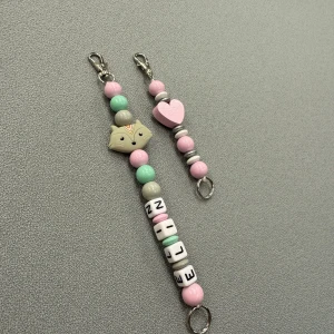 Personliga nyckelringar med pärlor - Här ser ni två av våra modeller. Till höger är vår nyckelring som är ca 10 cm lång. Till vänster är vårt korta pärlband på ca 23 cm. Nyckelknippan går på 69kr och nyckelbandet på 149kr. Det är upp till kunden att välja färg, bokstäver samt motivpärlor. OBS nyckelknippan inkluderar inga bokstavspärlor.