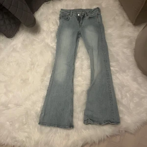 Blå bootcut jeans - Säljer ett par snygga blå low waist bootcut jeans från MONKI med klassisk femficksdesign. Jeansen har en ljus tvätt och är perfekta för en avslappnad stil. De har en knapp och dragkedja framtill. -pris kan diskuteras och vill du ha bild så får du skriva det