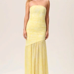 Gul axelbandslös klänning från Adoore - Elegant gul axelbandslös klänning från Adoore. Perfekt för sommarens festligheter med sin ljusa färg och stilrena look. Helt ny med prislapp