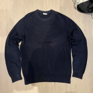 Filippa K knit - Säljer en mörkblå stickad tröja från Filippa K. Tröjan har en klassisk rund halsringning och långa ärmar. Den är storlek S men hyfsat stor i storleken så sitter bra på mig som bär M-L