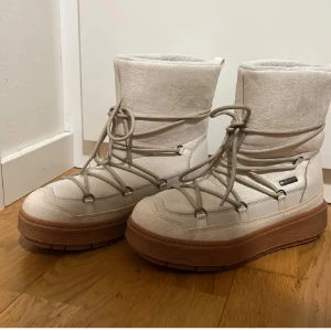 Vita moon boots med snörning – perfekt för vintern! - Säljer ett par vita moon boots i storlek 40 med snörning och tjock sula. De är både varma och bekväma, vilket gör dem perfekta för kalla vinterdagar. Den stilrena designen passar till alla vinterkläder och håller dina fötter varma även i snö och kyla. Skorna är i fint skick och redo att användas av nästa ägare! Skriv om ni vill ha mer bilder eller om ni har frågor om pris eller skorna. 