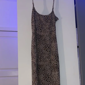 Leopardmönstrad långklänning - Trendig leopardmönstrad långklänning med smala axelband. Klänningen har en figurnära passform och är tillverkad i ett mjukt material. Väldigt lång, använd max 2 gånger. Unik då den var köpt utomlands 