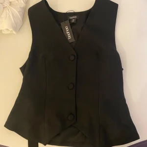 Svart topp väst från Boohoo - Snygg svart topp väst från Boohoo med knappar framtill. Helt ny med prislapp kvar