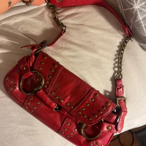 Röd axelväska med nitar vintage - Snygg röd axelväska i skinn med coola nitar och kedjedetaljer. 