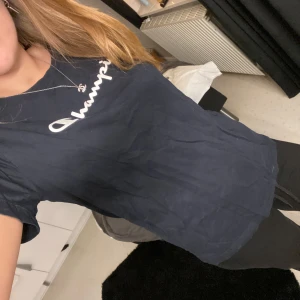 Marinblå t-shirt från Champion - Snygg marinblå t-shirt från Champion med deras ikoniska logga i vitt på bröstet. Perfekt för en avslappnad stil.