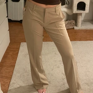 Lågmidjade kostymbyxor Nelly - Beige kostymbyxor från Nelly med låg midja och rak passform. Modell: ”low waist flare suit pants” i storlek 36. Dessa var väldigt stora i storleken och passade därför inte. Jag glömde returnera så jag säljer nu dessa billigt med prislappen kvar. De sitter som storlek 38. 