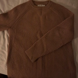 Beige stickad tröja från Calvin Klein - Säljer en snygg beige stickad tröja från Calvin Klein. Tröjan har en ribbad design och rund halsringning, perfekt för kyligare dagar. Den är i storlek M men passsar Xs och S också om man vill ha den oversized. 