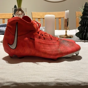  Nike phantom luna fotbollskor - Snygga röda Nike Phantom fotbollsskor med snörning och en stilren design. Perfekta för fotbollsplanen med sin lätta och smidiga konstruktion.