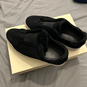 Svarta sneakers från Axel Arigato - Snygga svarta sneakers från Axel Arigato med en stilren design. Skorna har en vit sula och är perfekta för en avslappnad stil. De är tillverkade i ett mjukt material för extra komfort.